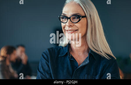 Close up Portrait von Senior Business Frau Tragen von Brillen steht im Amt. Reife weibliche im Büro mit Blick auf die Kamera zu lächeln. Stockfoto