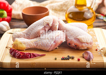 Raw Hähnchenschenkel mit Gewürzen auf einem Holzbrett Stockfoto