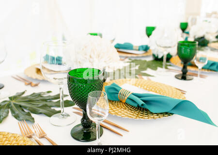 Innenraum des Zeltes für Hochzeit Diner, bereit für die Gäste. Runde Tafel im Freien serviert im Festzelt dekoriert Hortensienblüten, goldene Teller und Servietten. Catering Konzept Stockfoto