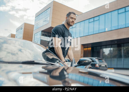 Nahaufnahme von jungen attraktiven Mann aus dem schwarzen Auto. Von der Seite. Stockfoto