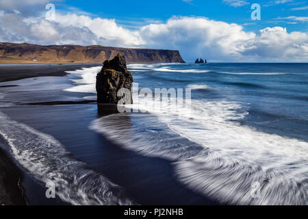 An der Südküste Islands dieser Lonely Rock Nadel ragt aus dem Meer und wird von den Wellen weggespült. Stockfoto