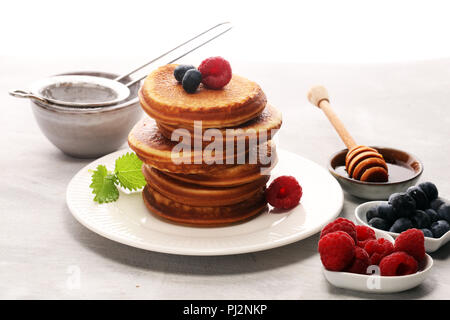 Pfannkuchen mit Beeren und Ahornsirup auf rustikalen Tisch. Stockfoto