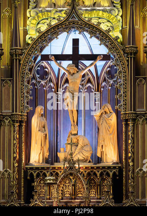 Eine aus Holz geschnitzte Kreuzigungsgruppe Skulptur mit Jesus am Kreuz, seiner Mutter Maria und Maria Magdalena an der Basis des Kreuzes. Die Skulptur ist die Stockfoto