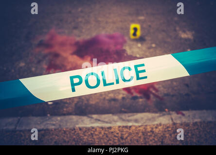 Ein Polizei Band neben dem Schauplatz eines gewaltsamen blutigen Verbrechen mit gelben Beweise Marker Stockfoto