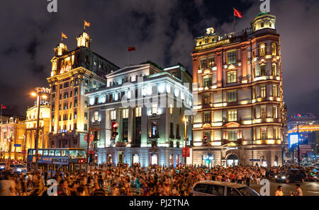 Masse der Touristen über die Straße von der Peace Hotel auf der East Nanjing Road zum Bund Promenade in Shanghai, China Pudong Light Show zu genießen. Stockfoto