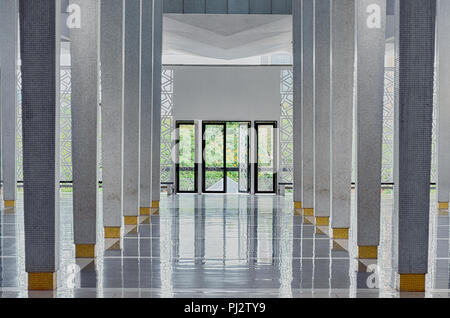 Langen Korridor zwischen vielen Säulen, Türen öffnen, im Ende, symmetrischen moderne Halle in nationalen Moschee (Masjid Negara), Kuala Lumpur, Malaysia. Functiona Stockfoto