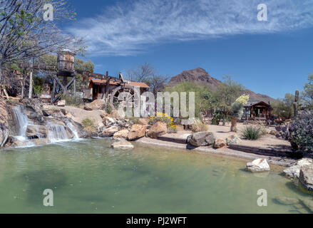 Teich mit Wasserfall und Wasserrad in der Wüste unter blauem Himmel in Old Tucson, Arizona. Stockfoto