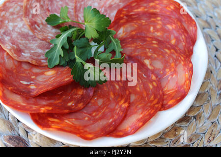 Chorizo und Salami in Scheiben geschnitten und serviert mit Petersilie auf eine weiße Platte, in der Nähe Stockfoto