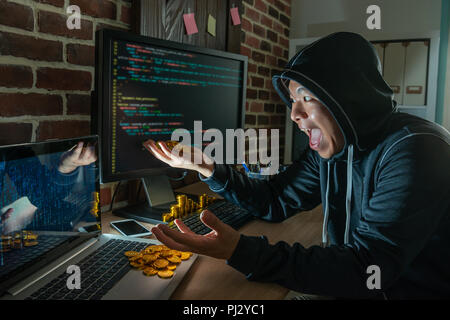 Männliche hacker glücklich lachend für Raub Lösegeld. packte einen Haufen bitcoin in seinen Händen. Stockfoto