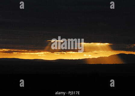 Was für ein toller Hintergrund! Brillante Lichtstrahlen Sonnenlicht, das durch die Bohrungen in der dunklen Gewitterwolken. In Südafrika fotografiert. Stockfoto