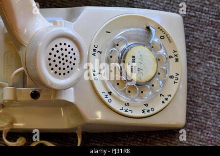 Eine alte creme oder beige Bell System analoge Drehregler Schreibtisch Telefon sitzt mit den Receiver aus dem Haken. Stockfoto