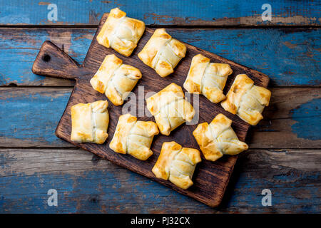 Mini empanadas auf Holzbrett, blauen Hintergrund. Ansicht von oben. Stockfoto