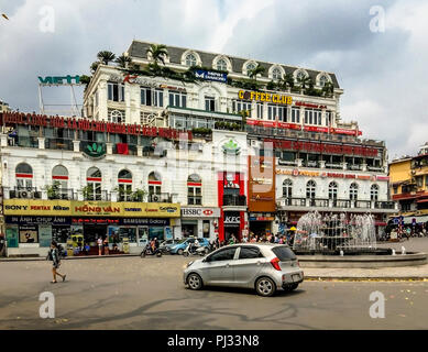 Quartal olOld Seeseite, Hanoi, Vietnam, 2/24/17, Autos um die Straße vor einem Gebäude voller Fast Food Restaurants gehen. Stockfoto