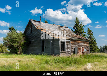 Alten, verlassenen prairie Bauernhaus durch Bäume, hohes Gras und blauer Himmel in Saskatchewan, Kanada umgeben Stockfoto