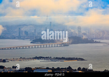 Anzeigen von Grizzly Peak in die Berkeley Hills auf die Bay Bridge und San Francisco mit Karl der Nebel umhüllt die Stadt bei Sonnenuntergang. Stockfoto