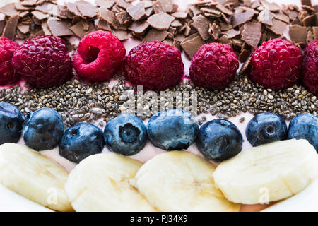 Einen Smoothie Schale mit frischen Beeren, Banane, Chia Samen und Schokolade für gesunde vegane und vegetarische Ernährung Frühstück Stockfoto