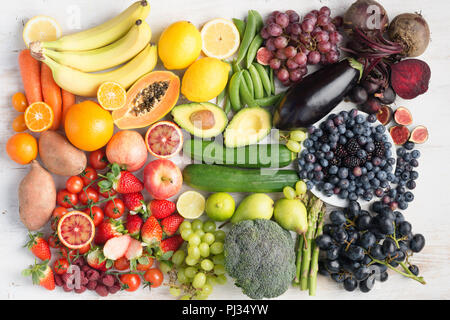 Gesunde Ernährung Konzept, Sortiment von Rainbow Obst und Gemüse, Beeren, Bananen, Orangen, Weintrauben, Brokkoli, rote Beete an der aus weissen Tisch in einem Rechteck, Ansicht von oben angeordnet, selektiver Fokus Stockfoto