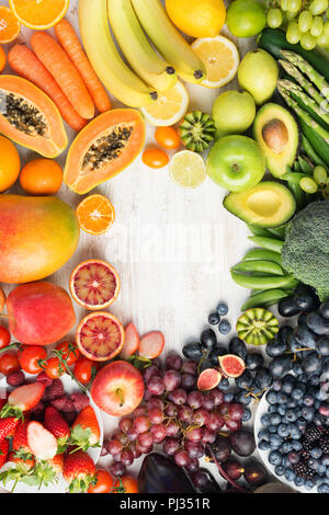 Das gesunde Essen, verschiedene Sorten von Obst und Gemüse in Regenbogenfarben an der aus weissen Tisch in einem Rahmen mit Kopie Raum angeordnet, Ansicht von oben, selektiver Fokus Stockfoto