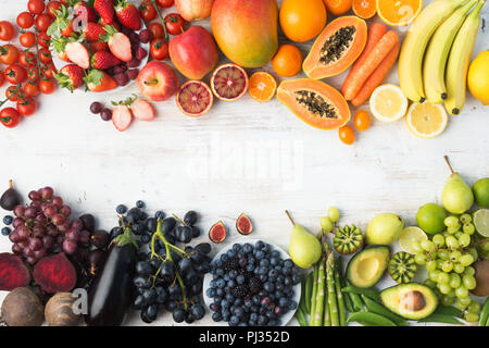 Das gesunde Essen Hintergrund, verschiedenen Sorten von bunten Obst und Gemüse in Regenbogenfarben an der aus weißen Tisch mit Kopie Raum in der Mitte, Ansicht von oben, selektiver Fokus Stockfoto