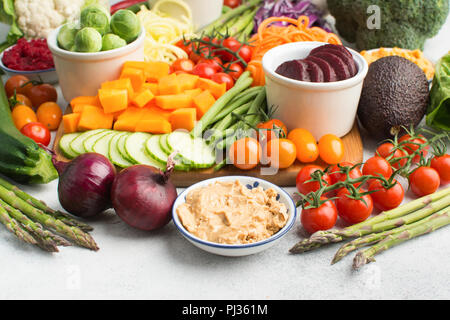 Auswahl an farbenfrohen Gemüse, Möhren, Zucchini, Kohl, Kichererbsen, Gurken und Tomaten, Blumenkohl und Brokkoli auf dem Holzbrett auf Weiß Stockfoto