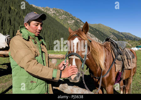 Altyn-Arashan, Kirgisistan, 14. August 2018: Eine junge Kirgisische liebevoll Anschläge ein Pferd in das Tal von Altyn-Arashan in Kirgisistan Stockfoto