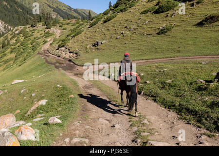 Altyn-Arashan, Kirgisistan, 14. August 2018: ein Reiter reitet einsam auf einem Weg im Tal des Altyn-Arashan in Kirgisistan Stockfoto