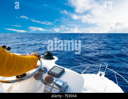 Hand von Captain am Lenkrad von Motorboot im blauen Ozean während der Fischerei. Erfolg angeln Konzept. Ocean Yacht. Stockfoto