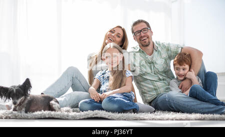 Freundliche Familie sitzt auf dem Teppich im neuen Wohnzimmer Stockfoto