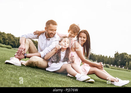 Kleben. Familie von vier Sitzen auf einer Wiese blasen Blase Stockfoto