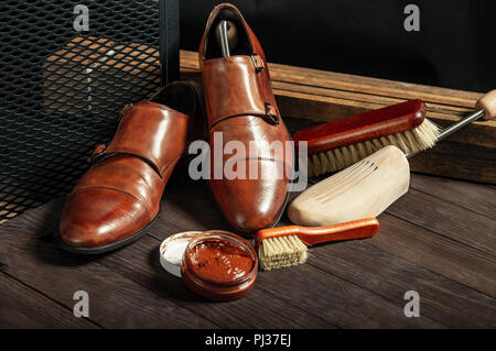 Schuhe aus Leder und Schuhcreme Ausrüstung auf einer hölzernen Zusammensetzung Stockfoto