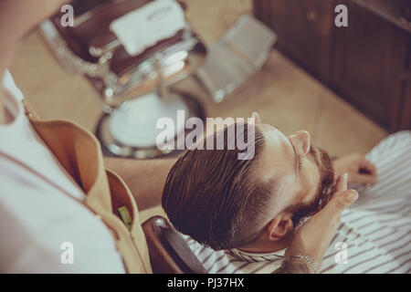 Der Friseur gilt der Bart Öl mit einem Dropper. Foto im Vintage Style Stockfoto