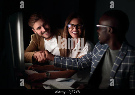 Mitarbeiter schütteln sich die Hände beim Sitzen am Schreibtisch Stockfoto