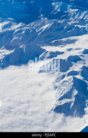 Einzigartige Luftaufnahme von beeindruckenden cumulus Gewitterwolken Körper über verschneite South Central Europe Mountain Region durch ein Flugzeug wi gesehen Stockfoto