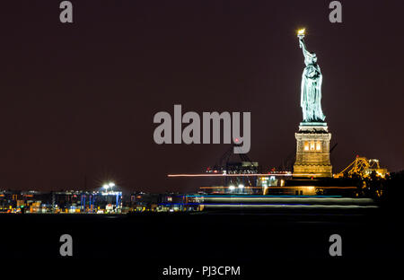 New York City. Long Shot Blick auf die Freiheitsstatue (Liberty erleuchten die Welt) in der Nacht, vom Battery Park. Eine kolossale neoklassischen Skulptur Stockfoto