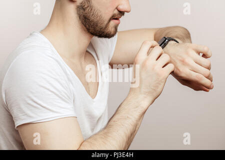 Der Mensch mit seinem Smart watch beim Stehen auf weißem Hintergrund Stockfoto