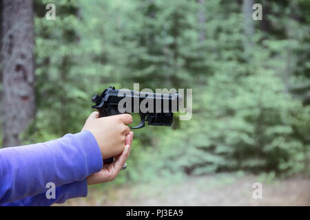 Frau schießt aus Luftgewehr Pistole (schwarz Air Gun) im Wald. Hände und Arme sichtbar, verschiedene Kamerawinkel Stockfoto