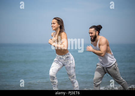 Glückliches Paar zusammen neben dem Wasser läuft am Strand Stockfoto