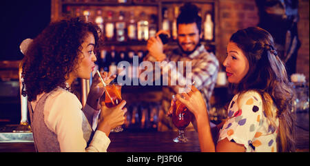 Zwei junge Frauen, die Cocktail Drinks am Zähler Stockfoto