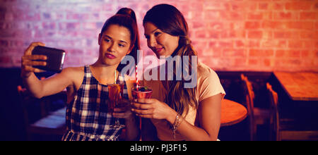 Junge Frauen, die ein selfie während mit Cocktail Drinks Stockfoto