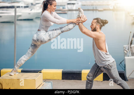 Männliche Trainer helfen jungen Frau Ausübung auf Pier. Stockfoto