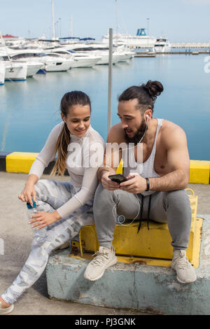 Paar hören die Musik zusammen mit einem Ohrhörer sitzen auf Pier Stockfoto