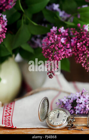 Antike Taschenuhr auf einer hölzernen Hintergrund, mit lila Blumen Stockfoto