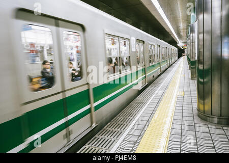 Der Blick auf den fahrenden Zug im Bahnhof von Osaka in Japan mit vielen Menschen sitzen im Inneren. Stockfoto