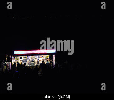 Cascais, Portugal - 19 August, 2018: die Nacht lange Belichtung mit hellen Leuchtreklame eines Fast Food stall verkaufen Churros und andere Süßigkeiten auf der Straße Stockfoto