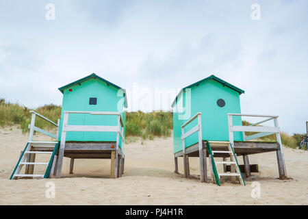 Kleiner Strand Häuser mit Stufen und ein Tor mit im Hintergrund Dünen mit dune Gras unter einem bewölkten Himmel Stockfoto