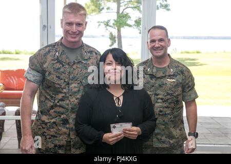 Bella Flynn (Mitte), Freiwilliger mit der Navy Marine Corps Fhv (NMCRS), erhält eine Auszeichnung für 1.500 Stunden widmen, zu helfen, Marines, Segler und ihre Familien von Colonel Russell Burton (links), kommandierender Offizier, Marine Corps Air Station (WAB) New River, und Oberst Christopher Bonifatius, kommandierender Offizier, Marine Flugzeuge Gruppe 26, an der Landung auf WAB New River, 12.08.29. Die NMCRS gab, die mehr als $ 600.000 in der Hilfe im Jahr 2017 und ihrer Fähigkeit, ihre Freiwilligen zu helfen. "Unsere Freiwilligen unserer Gesellschaft machen," sagte Casie Flippin, Direktor, NMCRS New River. "Die Freiwilligen Stockfoto