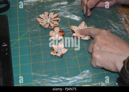 Die Frau Hände setzen letzten Schliff auf handgefertigtem Clover ornamentalen Blumen mit Kimono Material Stockfoto