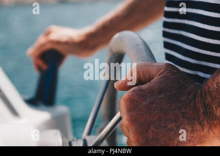 Nahaufnahme der Hand des älteren Kapitän am Lenkrad von Motorboot Stockfoto