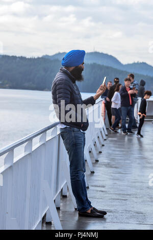 Passagier in chalm mit Telefon auf dem Deck, Fähre, Vancouver, Victoria, Kanada Stockfoto