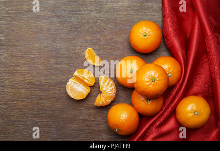 Das chinesische Neujahr - Mandarin orangen und roten Tuch auf hölzernen Tisch Stockfoto